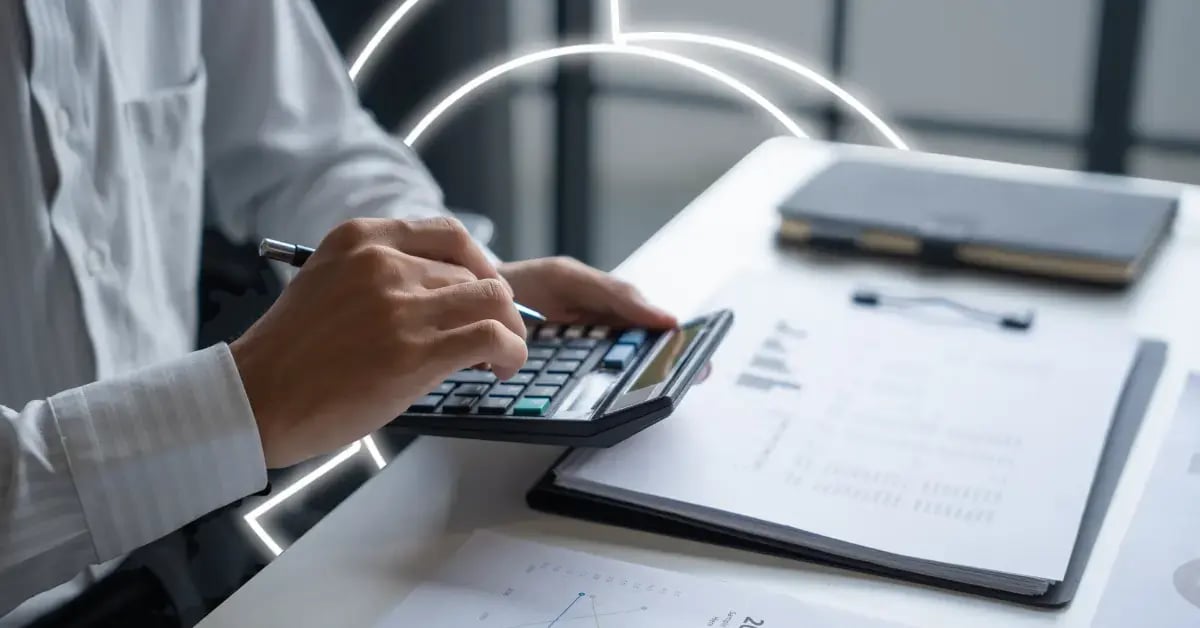 business professional at desk with papers and phone using calculator