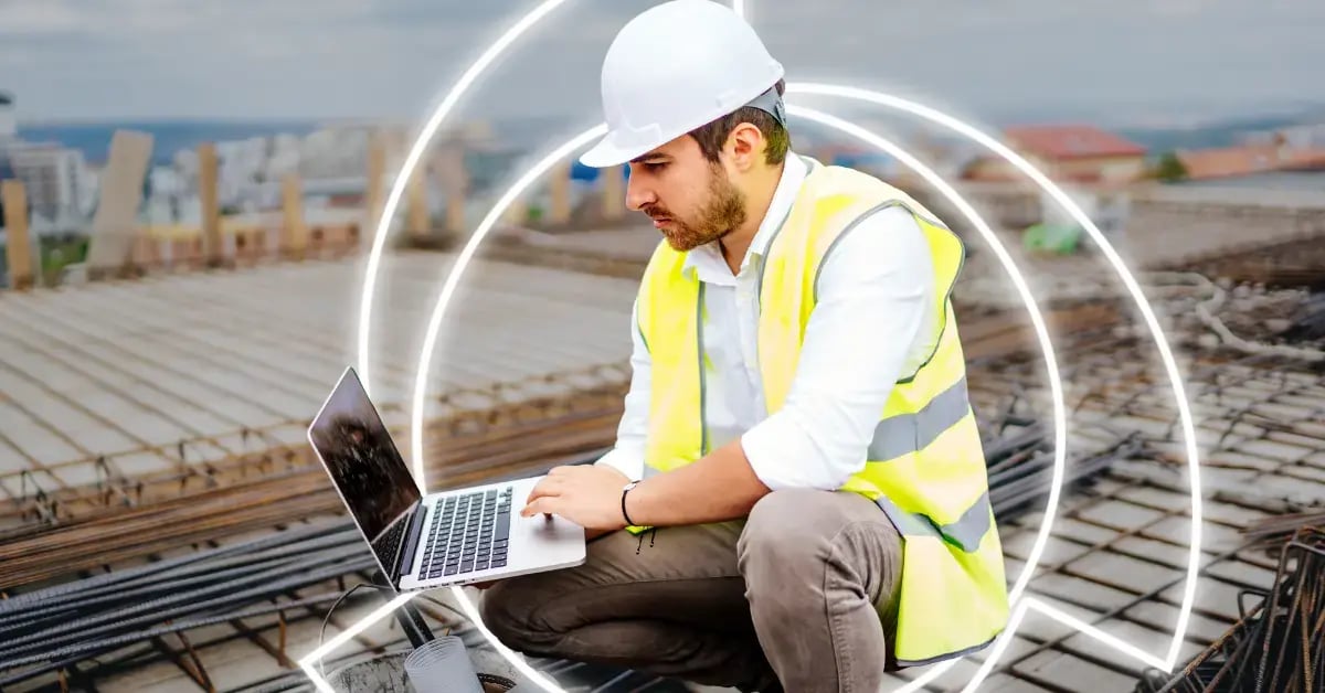 business man working on laptop in hardhat and safety vest on construction job site