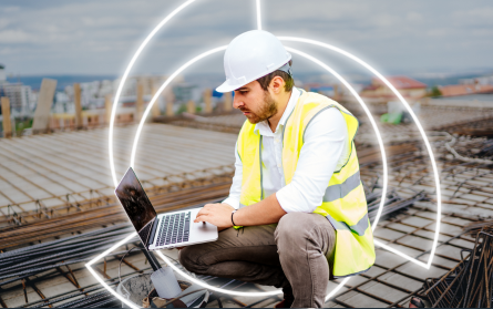man in hard hat and safety vest on job site working on computer