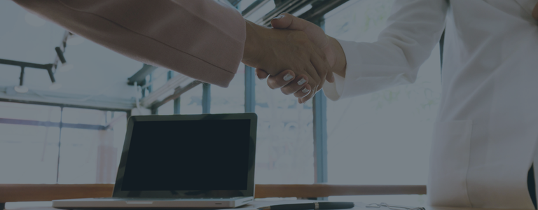 handshake over desk and computer