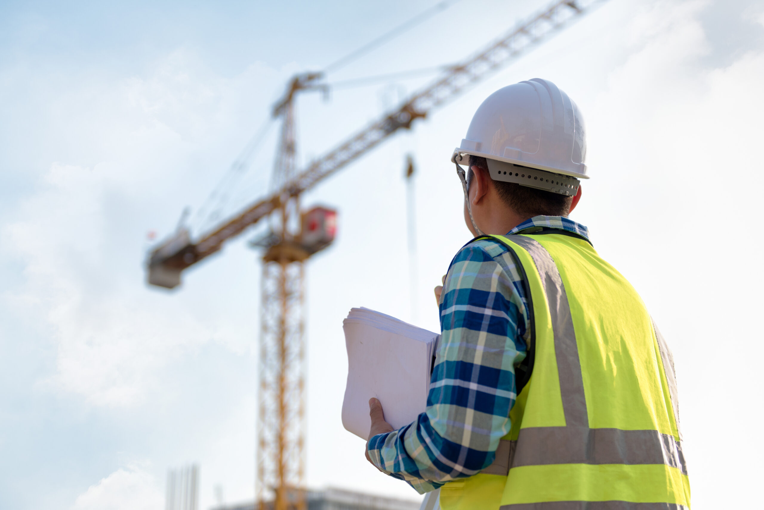 engineer looking up at a crane on a construction site