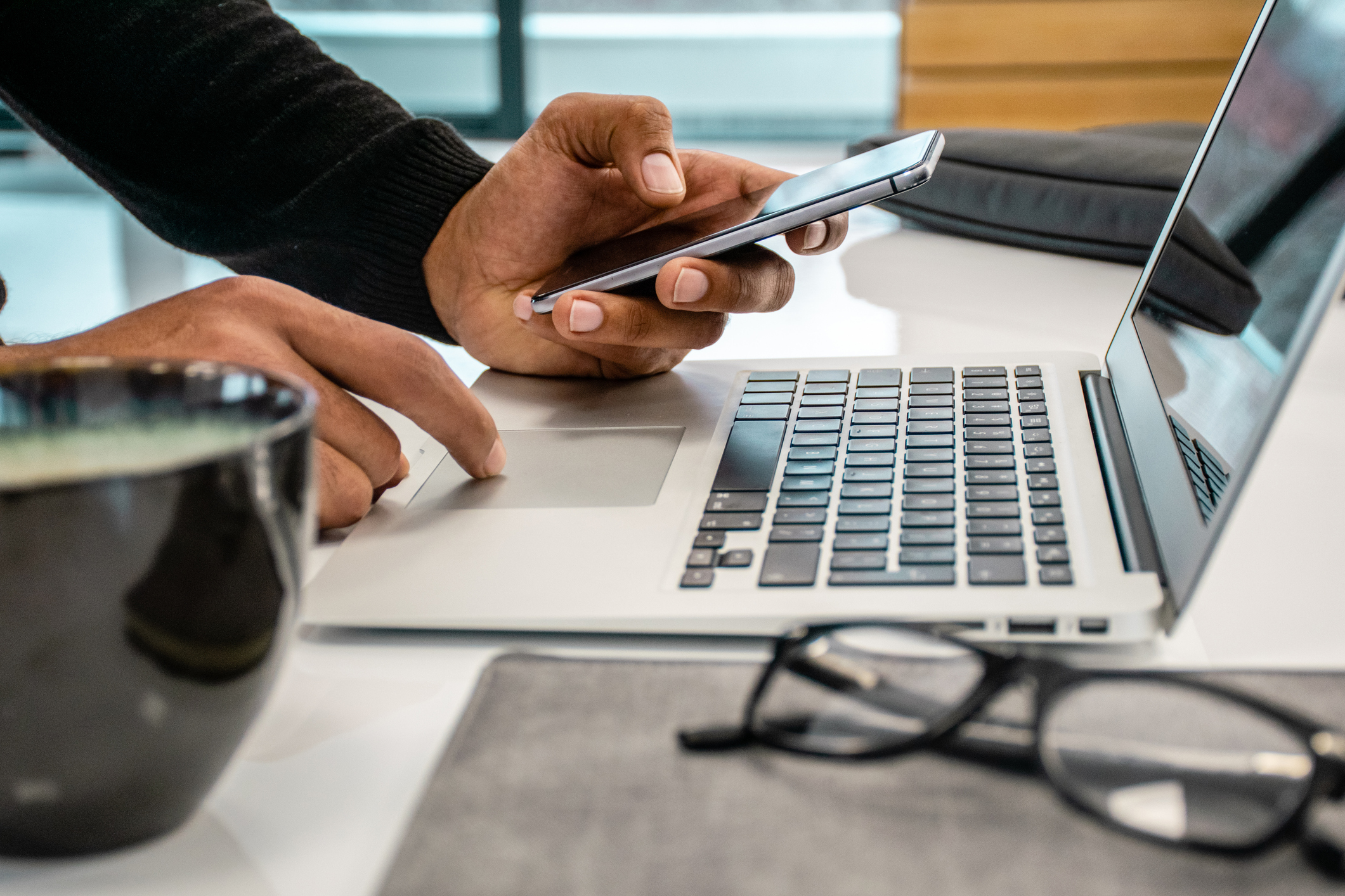 photo of man using phone and laptop